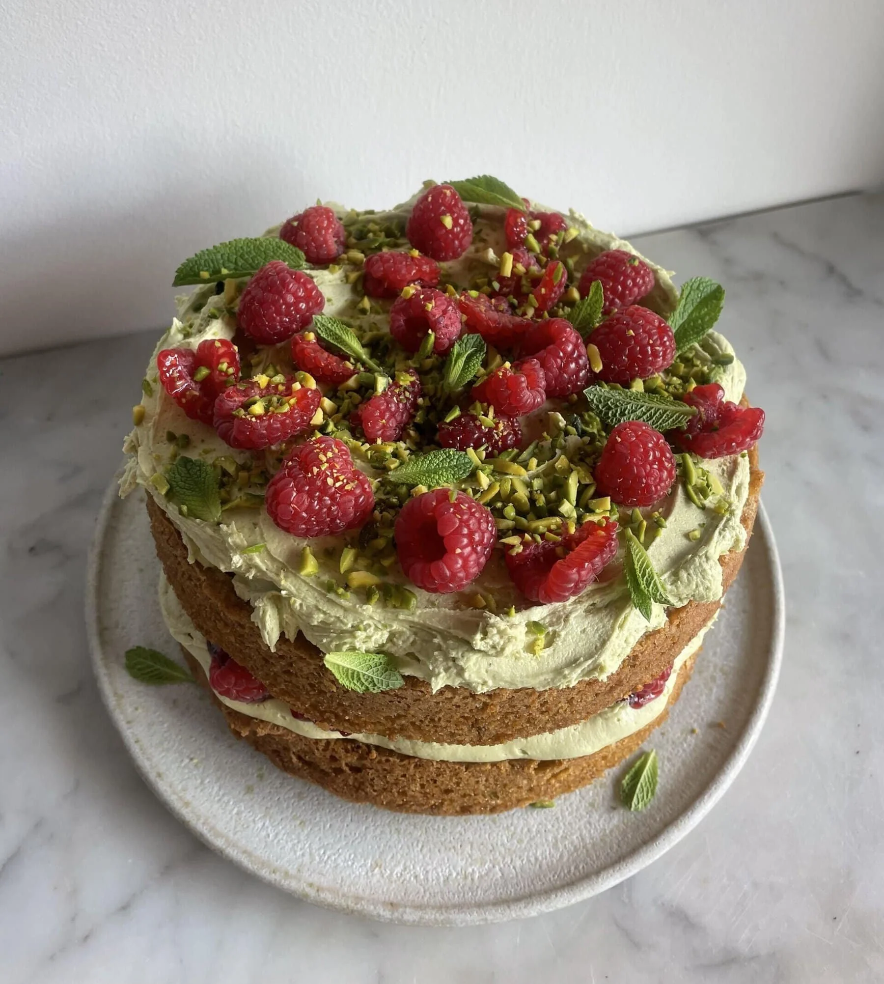 Slice of Pistachio Raspberry Cake with fresh raspberries and chopped pistachios