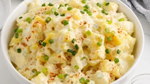 Delicious homemade Potato Salad served in a bowl with fresh ingredients.