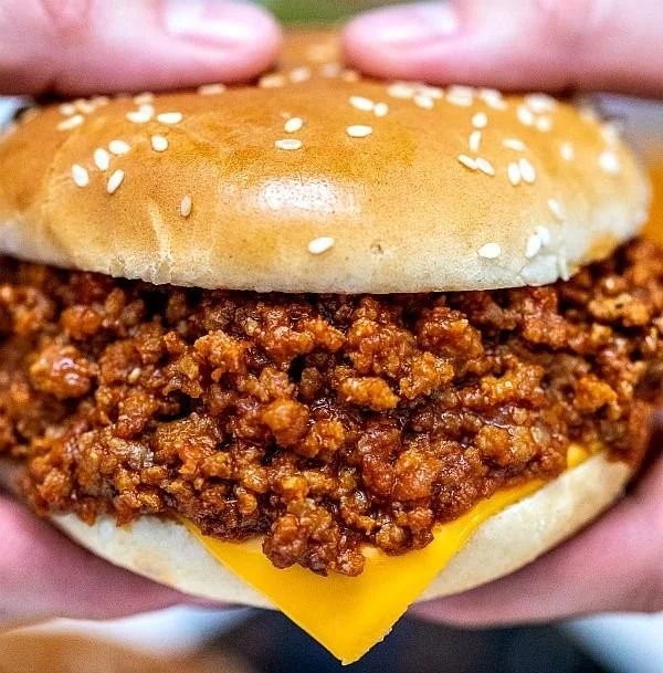 Slow Cooker Sloppy Joes served on a bun with a side of pickles
