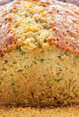 Loaf of moist zucchini bread with a slice cut out, showcasing its texture