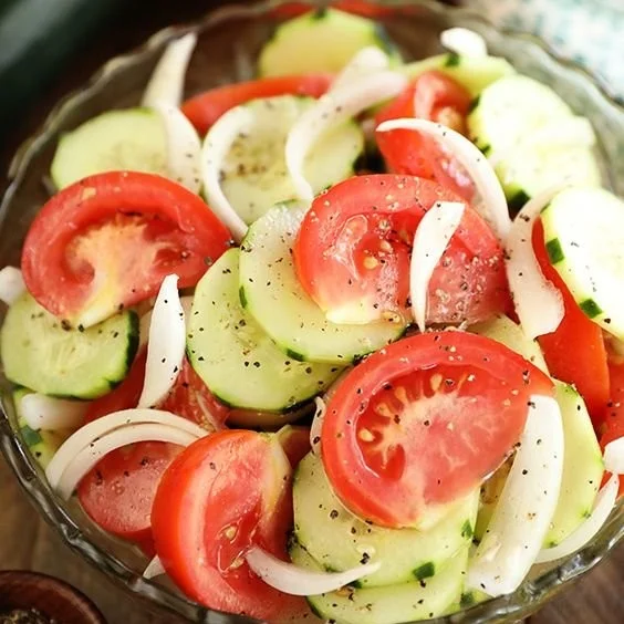 Fresh Tomato, Cucumber, and Onion Salad in a bowl, garnished with herbs.